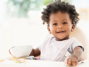 Toddler sitting and eating while smiling