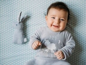 Little baby smiling while lying in bed.