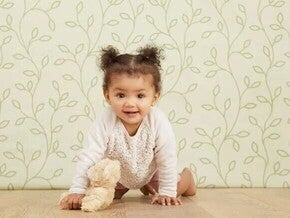 Babygirl crawling direct to the camera, holding a teddy bear