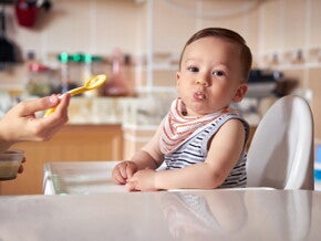 At their six months of age your baby should be ready for infant solid food. A baby being fed with infant solid foods.