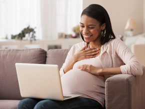 Pregnant woman sitting on laptop reading about pre-eclampsia