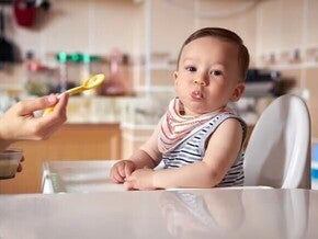 Baby being feed solid food