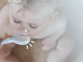 Toddler eating puree from a plastic spoon