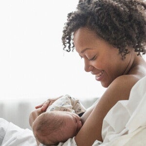A young mother smiling while she breastfeeds her baby