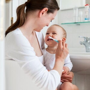 Children’s dental care is important for e healthy development. A mother taking care of her children’s dental care