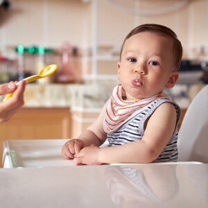 A baby being fed with infant solid foods.