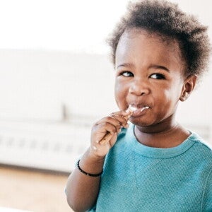 A baby being fed food from a baby meal planner.