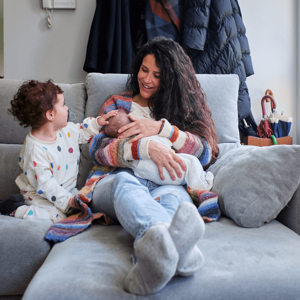 A mom enjoying breastfeeding benefits with her baby alongside her toddler.