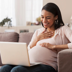 Pregnant woman sitting on laptop reading about pre-eclampsia