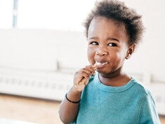 A baby being fed food from a baby meal planner.