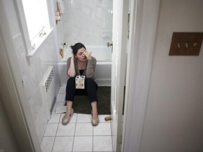 A woman sitting in the bathroom dealing with morning sickness