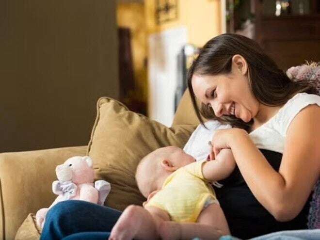 Mom feeding her baby with breast milk, while looking at him with a smile