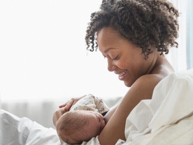 A young mother smiling while she breastfeeds her baby