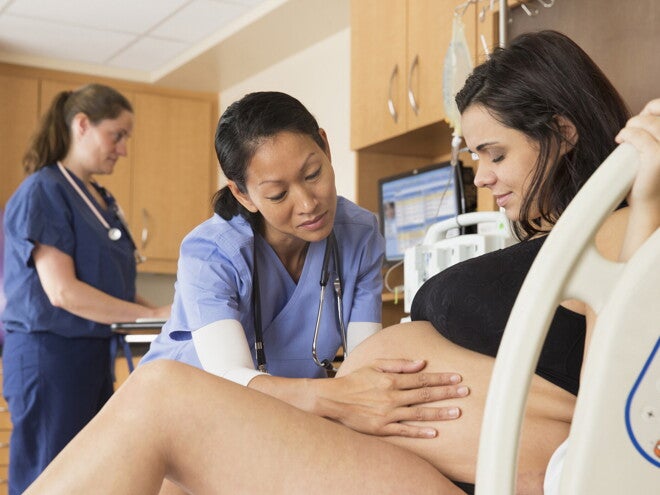 Learn more about C-sections and when they are needed during labor. Doctor examining the belly of a pregnant woman before C-sections.