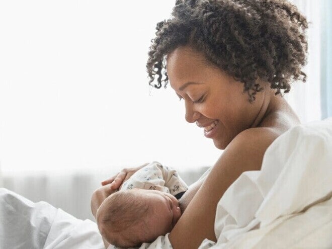 A young mother smiling while she breastfeeds her baby