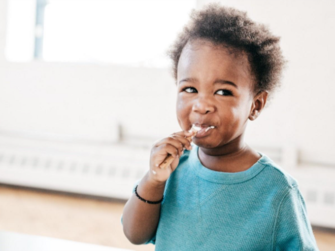 A baby being fed food from a baby meal planner.