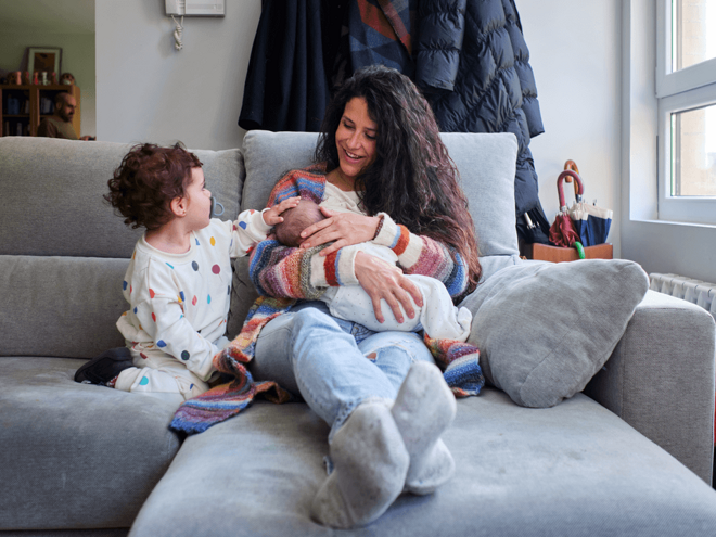 Get to know the breastfeeding benefits for you and your baby. A mom enjoying breastfeeding benefits with her baby alongside her toddler.