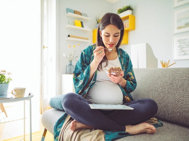 Pregnancy cravings are a common part of the gestation process A woman indulging her pregnancy cravings in her home.
