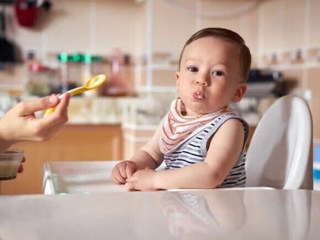Baby being feed solid food