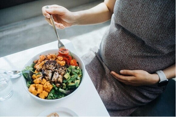 A pregnant woman eating a salad to avoid morning sickness