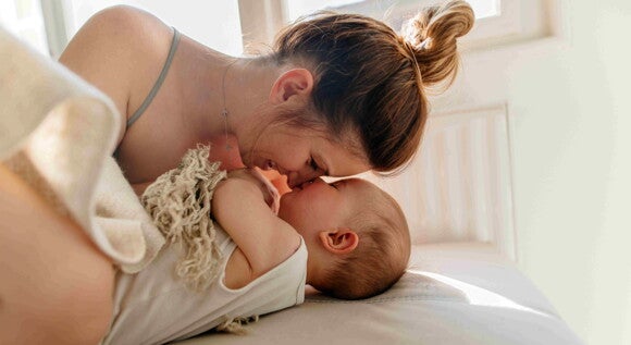 Breastfeeding sometimes can be challenging. A mom enjoying quality time with his baby in bed.