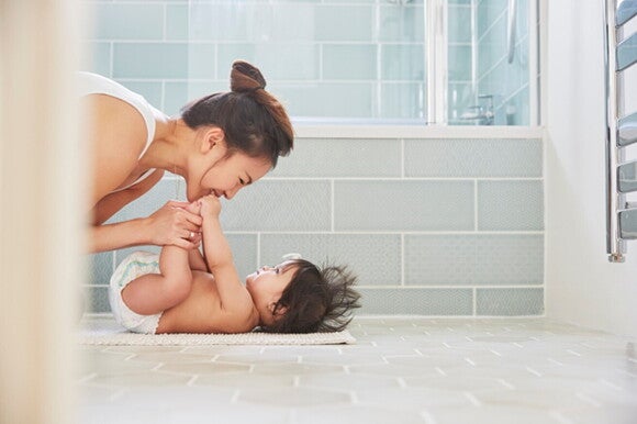 It’s important to be aware of any change in baby poo. A mother playing with her baby after changing her diaper.