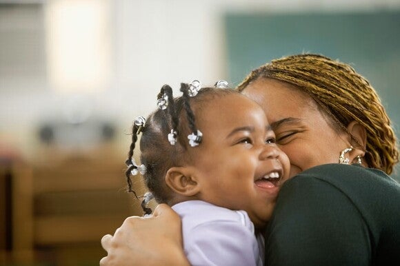 Toddler smiling and being hugged by her mother