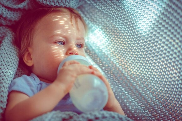 Baby’s tummy problems can appear even from feeding from a bottle. A toddler drinking milk from his bottle.