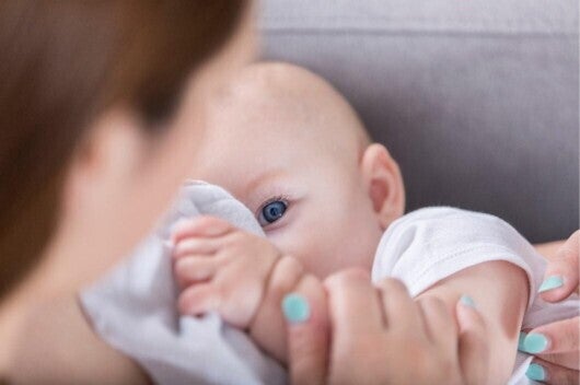 A baby looking at their mother while breastfeeding
