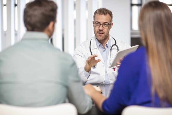 Learn more about the details of C-sections with your doctor. Doctor talking to a couple about the complications of C-sections.