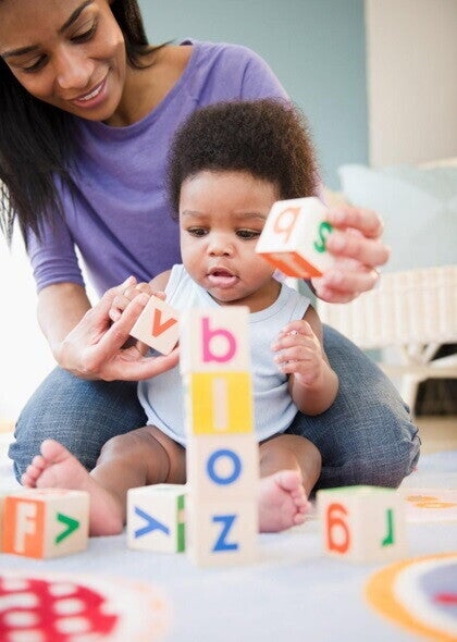 A baby girl an her mother playing with blocks