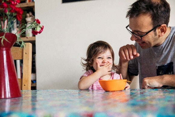 It is important to ensure a positive atmosphere in every family meal for toddlers A dad sharing a family meal for toddlers with his daughter.