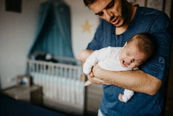A dad holding his baby, trying to calm him down while his crying