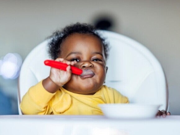 A baby feeding herself with a spoon.