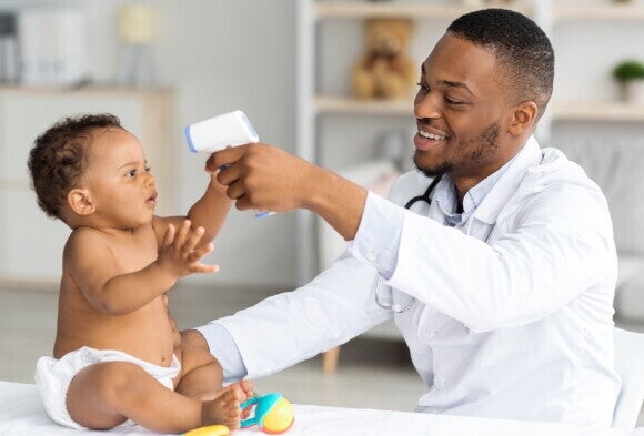 A baby with his pediatrician after being vaccinated.