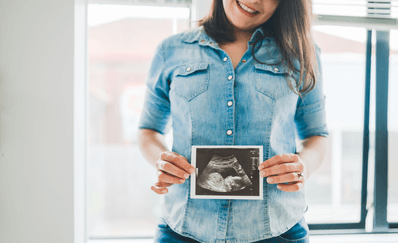 The first trimester is the moment where all the important organs develop. A woman with the picture of and echo in her belly after the first trimester.