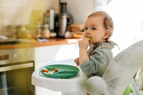 It’s important to promote self-feeding in a toddler diet A toddler feeding himself with vegetables.